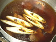 鴨汁の入った鍋を火にかけ、焼き目を付けた長ネギを加えます。